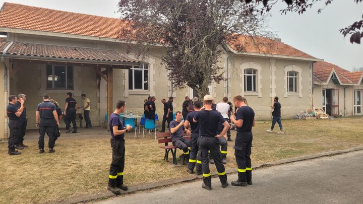 Les pompiers qui ont lutté contre l'incendie toute la nuit de lundi à mardi prennent quelques minutes de repos à Louchats, village évacué par les autorités, le 19 juillet 2022. (THOMAS GIREAUDAU / RADIO FRANCE)