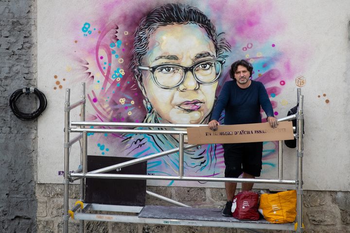 L'artiste Christian Guerny, alias C215, pose le 3 juin 2020 à Saint-Ouen devant l'œuvre murale qu'il a réalisée en mémoire d'Aïcha Issadounène, caissière emportée par le Covid-19 (JOEL SAGET / AFP)