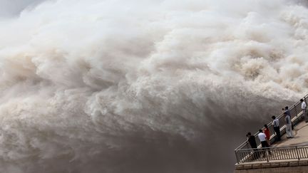 Des spectateurs assistent &agrave; l'&eacute;vacuation de millions de tonnes d'eau et de s&eacute;diments vers l'oc&eacute;an afin de contr&ocirc;ler le niveau du fleuve Jaune &agrave;&nbsp;Xiaolangdi (Chine), le 23 juillet 2013. (AFP)