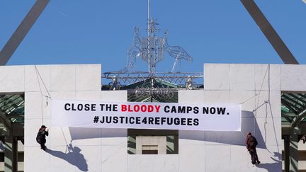 Des manifestants déploient une banderole, le 1er décembre 2016, au Parlement à Canberra (Australie) pour réclamer la fermeture des camps de détention offshore de migrants.&nbsp; (NATHANIAL HOWELLS / AFP)