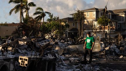 Un homme regarde les dommages causés par un incendie de forêt à Lahaina, dans l'ouest de Maui, à Hawaï, le 12 août 2023. (YUKI IWAMURA / AFP)