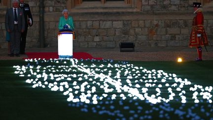 Au château de Windsor, la reine Elizabeth II&nbsp;allume le "Principal Beacon" (le "phare principal"), le premier des milliers de symboles lumineux que le Royaume-Uni et le Commonwealth&nbsp;qui s'allument pour lui rendre hommage, dont une sculpture de 21 mètres de haut en forme d'arbre, éclairée par la reine elle-même, le 2 juin 2022. (ADRIAN DENNIS / AFP)