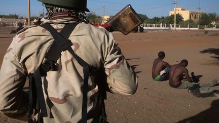 Un soldat malien surveile deux jihadistes pr&eacute;sum&eacute;s &agrave; Gao&nbsp;au Mali, le 22 f&eacute;vrier 2013. (JOEL SAGET / AFP)