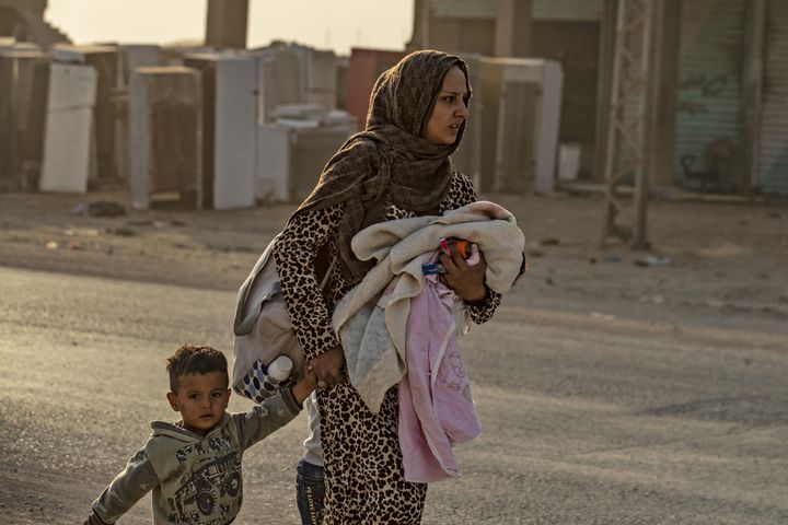 Une femme kurde et son fils fuient le village de Ras al-Aïn, le 9 octobre 2019, alors que les premières frappes turques commencent. (DELIL SOULEIMAN / AFP)