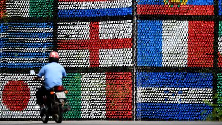 Un motard passe devant un mur de drapeaux, &agrave; Porto Seguro (Br&eacute;sil), le 18 juin 2014. (PATRIK STOLLARZ / AFP)