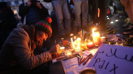 Une femme rend hommage aux victimes des attentats de Paris, le 11 janvier 2015, au pied de la statue situ&eacute;e sur la place de la R&eacute;publique. (  MAXPPP)