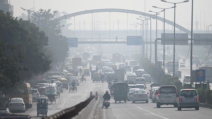 Des automobilistes se frayent un chemin le long d'une route au milieu d'un épais brouillard lié à la pollution à New Delhi, le 16 novembre 2021. (MONEY SHARMA / AFP)