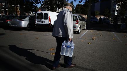 Un homme récupère un pack d'eau à&nbsp;Yvetot (Seine-Maritime) après l'interdiction de consommation de l'eau du robinet. (CHARLY TRIBALLEAU / AFP)