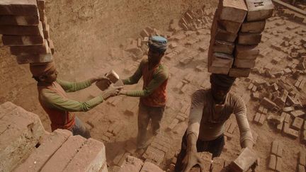 les ouvriers, couverts d'une épaisse poussière, travaillent dans les mêmes conditions qu'il y a 150 ans: briques façonnées à la main, posées manuellement dans les fours et transportées à dos d'homme, ou plus exactement sur la tête, comme le montre cette photo. Chaque travailleur peut y empiler jusqu'à 20 briques. (MD. Mehedi Hasan/PACIFIC /SIPA)