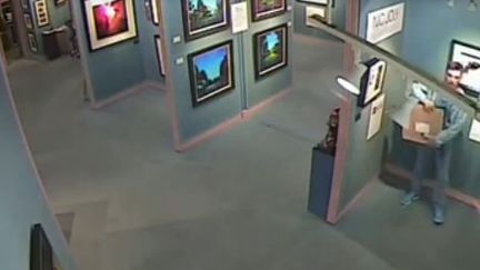 Capture d'&eacute;cran d'une videosurveillance publi&eacute;e par la police de&nbsp;Birmingham (Royaume-Uni) montrant un visiteur d'uen galerie d'art d&eacute;rob&eacute; un tableau, le 17 aout 2014. (NEWSFORALL / YOUTUBE)