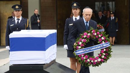 Simon Peres d&eacute;pose une couronne de fleurs devant le cercueil de son "cher ami", qui&nbsp;"ne connaissait pas la peur et n'a jamais craint de poursuivre un id&eacute;al." (URIEL SINAI / GETTY IMAGES)