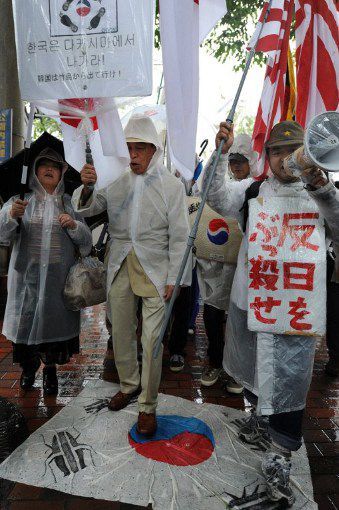 Des membres du mouvement d'extrême-droite Zaitokukai foulent au pied le drapeau coréen à Tokyo. (AFP PHOTO / TORU YAMANAKA)