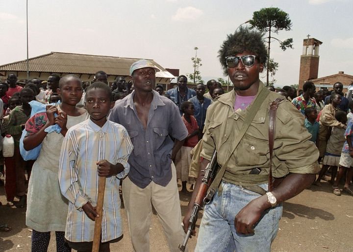 Des miliciens hutus assistent &agrave; l'&eacute;vacuation, par les Nations unies, de 400 Tutsis de l'&eacute;glise de la Sainte-Famille, &agrave; Kigali,&nbsp;le 13 juin 1994. (ABDELHAK SENNA / AFP)