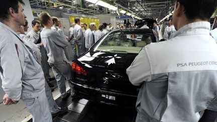 Des ouvriers de l'usine PSA de Sochaux (Franche-Comt&eacute;)&nbsp;rassembl&eacute;s autour de la derni&egrave;re Peugeot 607 produit dans la m&ecirc;me usine, le 4 mars 2009. (SEBASTIEN BOZON / AFP)