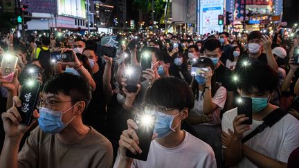 Des manifestants brandissent les torches de leurs téléphones portables, pendant un rassemblement à Hong Kong, le 12 juin 2020. (ANTHONY WALLACE / AFP)