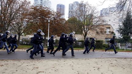 Des policiers en train de courir durant les incidents du 19 octobre à Nanterre (Hauts-de-Seine). (AFP - THOMAS SAMSON)