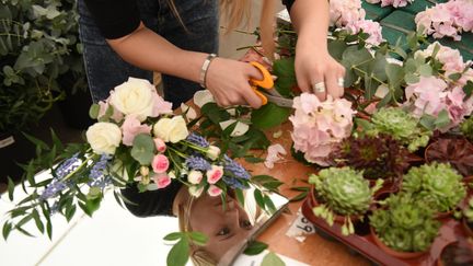 Une fleuriste en train d'élaborer un bouquet. (OLI SCARFF / AFP)