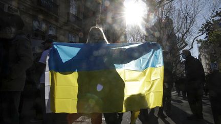 Une femme portant un drapeau ukrainien lors d'une manifestation contre la guerre dans ce pays, à Paris, le 27 février 2022. (GEOFFROY VAN DER HASSELT / AFP)