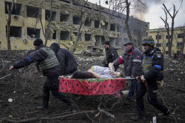 Des employés et des bénévoles des services d'urgence ukrainiens transportent une femme enceinte blessée hors d'une maternité endommagée par des bombardements à Marioupol, en Ukraine, le 9 mars 2022. La femme et son bébé sont morts après que la Russie a bombardé la maternité où elle devait accoucher.&nbsp; (EVGENIY MALOLETKA / AP)