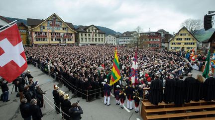 Les gens lèvent les mains pour voter lors de la réunion annuelle de Landsgemeinde sur une place de la ville d'Appenzell, dans l'est de la Suisse, le 28 avril 2013. (SEBASTIEN BOZON / AFP)