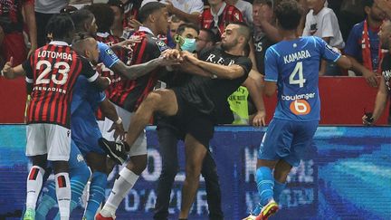 Un supporter tente de s'en prendre à Dimitri Payet lors de l'envahissement du terrain de l'Allianz Riviera en marge de Nice-Marseille, le 22 août 2021. (VALERY HACHE / AFP)