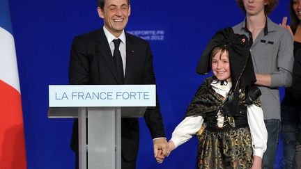 Le pr&eacute;sident candidat Nicolas Sarkozy&nbsp;(G) au c&ocirc;t&eacute; d'une petite fille en habit traditionnel alsacien lors de son meeting &agrave; Cernay (Haut-Rhin), le 25 avril 2012. (FREDERICK FLORIN / AFP)