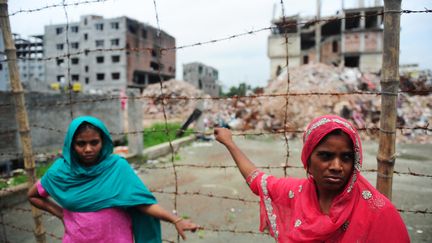 Deux ouvri&egrave;res textiles devant le b&acirc;timent effondr&eacute; dans lequel&nbsp;elles travaillaient &agrave; Dacca, au Bangladesh, le 24 juin 2013. (MUNIR UZ ZAMAN / AFP)