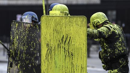 Des CRS sont couverts de peinture jaune, aux abords des Champs-Elysées, le 1er décembre 2018. (ALAIN JOCARD / AFP)