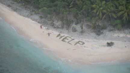 Deux des trois naufragés de l'île Fanadik, dans le Pacifique, font signe à l'équipage d'un avion de la marine américaine, le 7 avril 2016. (US PACIFIC FLEET / FLICKR)