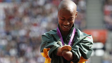 Le Sud-Africain Samkelo Radebe regarde sa m&eacute;daille d'or gagn&eacute;e au relais 4x100 m aux Jeux paralympiques de Londres (Royaume-Uni), le 6 septembre 2012. (SUZANNE PLUNKETT / REUTERS)