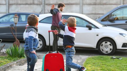 Des enfants, valise à la main, disent au revoir à leur père. Photo d'illustration. (GAUJARD CHRISTELLE / MAXPPP)