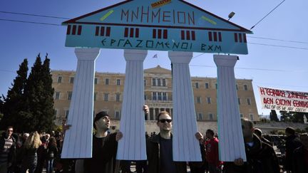 Des employ&eacute;s grecs du mus&eacute;e byzantin et chr&eacute;tien d'Ath&egrave;nes tiennent un panneau avec &eacute;crit dessus : "Monument &agrave; vendre", le 19 f&eacute;vrier 2012 lors d'une manifestation. (LOUISA GOULIAMAKI / AFP)