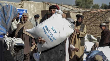 Des Afghans portent des sacs distribués au titre de l'aide humanitaire, à Kandahar, le 19 octobre 2021. (JAVED TANVEER / AFP)