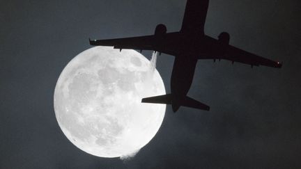 Un avion passe devant la "super Lune" à proximité de l'aéroport d'Heathrow, à Londres (Royaume-Uni), le 1er janvier 2018. (JUSTIN TALLIS / AFP)