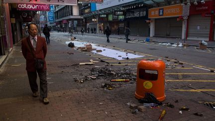 Un passant marche le 9 février 2016 à proximité des débris laissés par une nuit d'émeutes dans le quartier de Mongkok, à Hong Kong. Une centaine de personnes, dont de nombreux policiers, ont été blessées lors de ces incidents survenus aux premières heures, alors que les habitants de l'ancienne colonie britannique fêtaient le Nouvel an chinois. Les troubles ont éclaté lorsque les autorités ont tenté de disperser des vendeurs ambulants non autorisés qui proposaient, entre autres, de la nourriture. Les manifestants, parmi lesquels des membres de la mouvance dite «localiste» qui milite contre l'influence de Pékin à Hong Kong et réclame même parfois l'indépendance de l'archipel, tentaient de prendre la défense des vendeurs, arguant qu'ils participaient à l'atmosphère festive en ce début d'année du singe. (DALE DE LA REY / AFP)