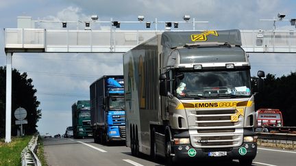 Des camions passent sous un portique destiné à l'écotaxe en juin 2013, avant l'abandon du projet&nbsp; (PHILIPPE HUGUEN / AFP)