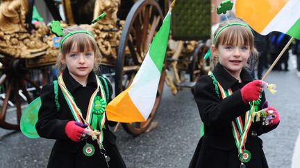 A Dublin (Irlande), deux petites filles agitent le drapeau national lors du d&eacute;fil&eacute; traditionnel de la Saint Patrick. (KIM HAUGHTON / MAXPPP)