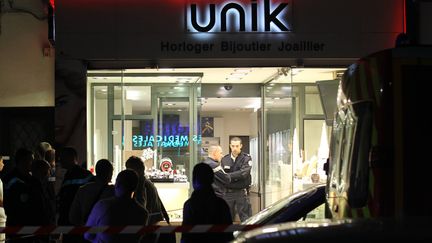 Des policiers montent la garde &agrave; l'entr&eacute;e de la bijouterie Unik de Cannes (Alpes-Maritimes), vis&eacute;e par un braquage mortel, le 26 novembre 2011. (VALERY HACHE / AFP)