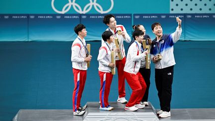 Les pongistes nord coréens Ri Jong Sik et Kim Kum Yong (les deux plus à gauche), lors de la remise de médailles du double mixte de tennis de table, le 30 juillet 2024 aux JO de Paris. (WANG Zhao / AFP)