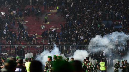 Des supporters de football sont pris dans une bousculade alors que les forces de sécurité interviennent sur la pelouse d'un stade à Malang (Indonésie), le 1er octobre 2022. (STR / AFP)