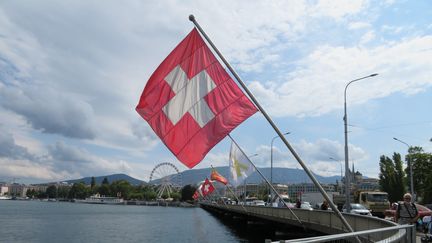 Vue sur le bord du lac Léman à Genève en Suisse, avec un drapeau suisse au premier plan, fin août 2018. (STÉPHANE MILHOMME / FRANCE-INFO)