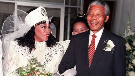 Zindzi Mandela souriante, au bras de son père Nelson Mandela, et en tenue traditionnelle xhosa pour son marriage avec l'homme d'affaires Zweli Hlongwane, le 26 octobre 1992 à Soweto,&nbsp;en Afrique du Sud.&nbsp; (WALTER DHLADHLA / AFP FILES)