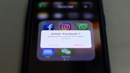 Un utilisateur hésite à supprimer Facebook de son téléphone, le 27 mars 2018. (CHANDAN KHANNA / AFP)