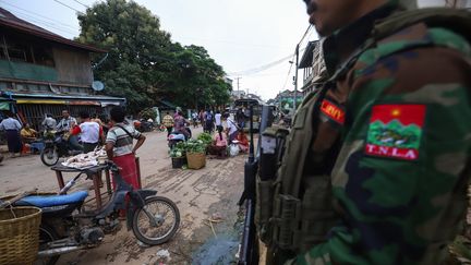 Un membre du groupe armé ethnique Ta'ang National Liberation Army fait le guet pendant que les gens achètent des provisions sur un marché à Kyaukme, dans l'Etat de Shan, en Birmanie, le 2 juillet 2024. (STR / AFP)