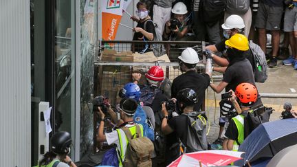 Des manifestants tentent de briser les vitres du Parlement, le 1er juillet 2019 à Hong Kong (Chine). (VIVEK PRAKASH / AFP)