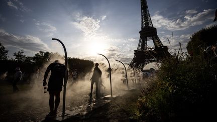 Des personnes se rafraîchissent à côté de la tour Eiffel, à Paris, le 29 juillet 2024. (LUIS TATO / AFP)