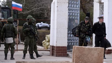 Des militaires ukrainiens (&agrave; droite), quittant le quartier g&eacute;n&eacute;ral de la marine ukrainienne &agrave; Sebastopol (Crim&eacute;e), pass&eacute; sous le contr&ocirc;le de milices pro-russes (&agrave; gauche), le 19 mars 2014. (FILIPPO MONTEFORTE / AFP)