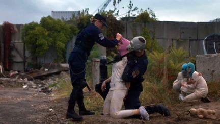 Une femme policier à l'uniforme américain, une arrestation musclée, des enfants et des cagoules colorées emblématiques du groupe Pussy Riot, dans le nouveau clip des artistes militantes...
 (Capture image YouTube)