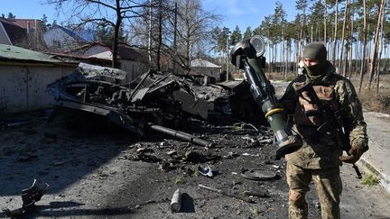 Un soldat ukrainien devant un char russe détruit par un missile à Irpin au nord de Kiev (Ukraine), le 12 mars 2022. (AFP)