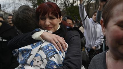 Un adolescent embrasse sa maman après l'arrivée du bus qui le transportait avec plus d'une douzaine d'autres enfants du territoire sous contrôle russe, à Kiev le 22 mars 2023. (SERGEI CHUZAVKOV / AFP)